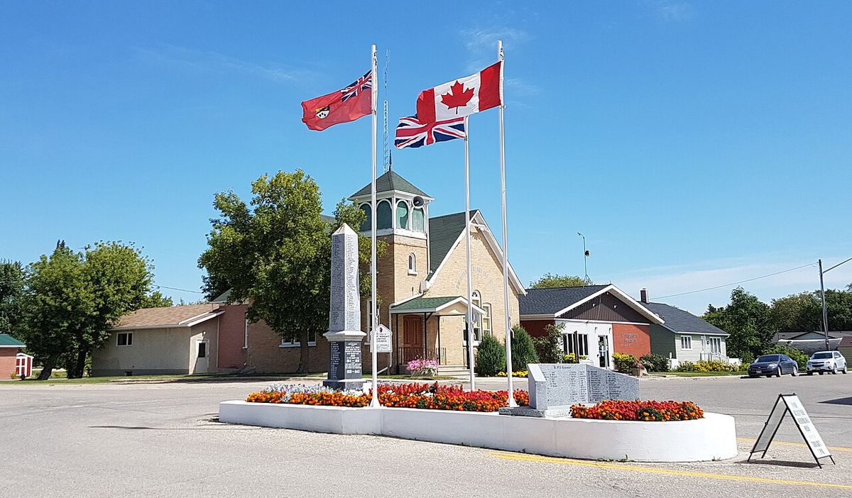 A view of Cartwright Manitoba, with the war cenotaph and flags in the foreground.