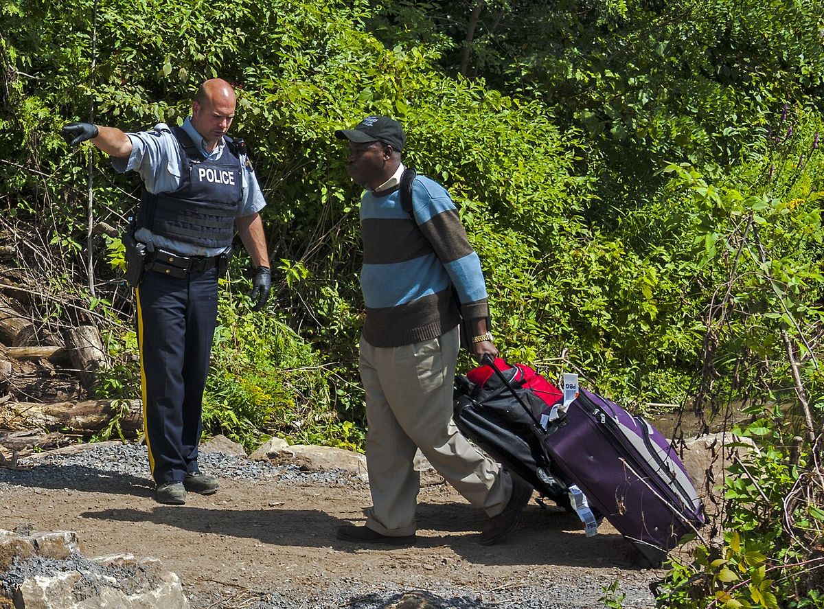 An asylum seeker, crossing the US-Canadian border from the end of Roxham Road in Champlain, NY, is directed to the nearby processing center
