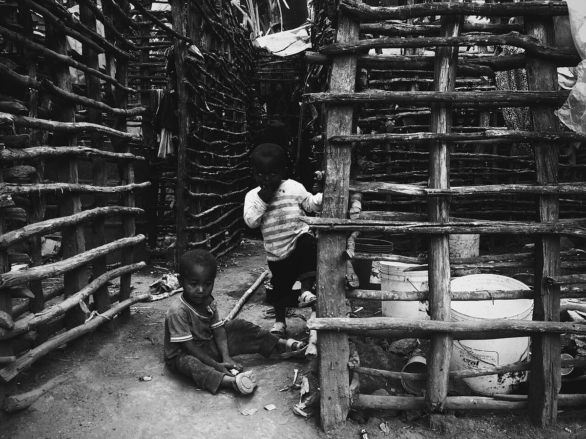 A picture taken at Mashati, Kilimanjaro region Tanzania. One kid playing with a stone as a car and the other holding the frame of their side