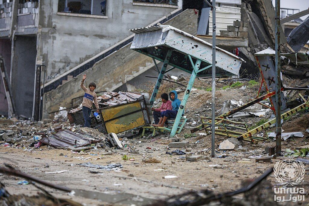 Displaced children sit on the rubble of their destroyed home in Nuseirat camp, Gaza Strip.