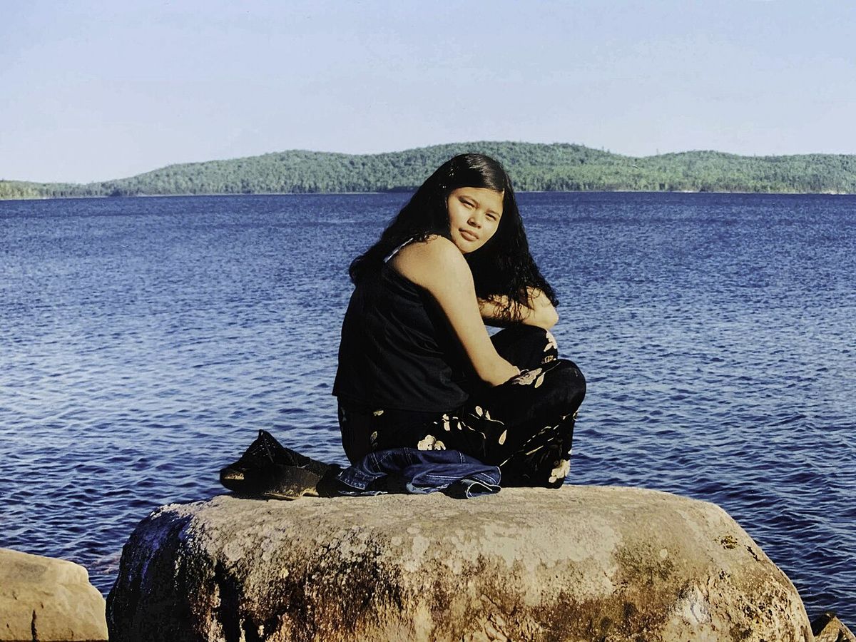 Photo de Joyce Echaquan quand elle était jeune fille assise au bord du lac