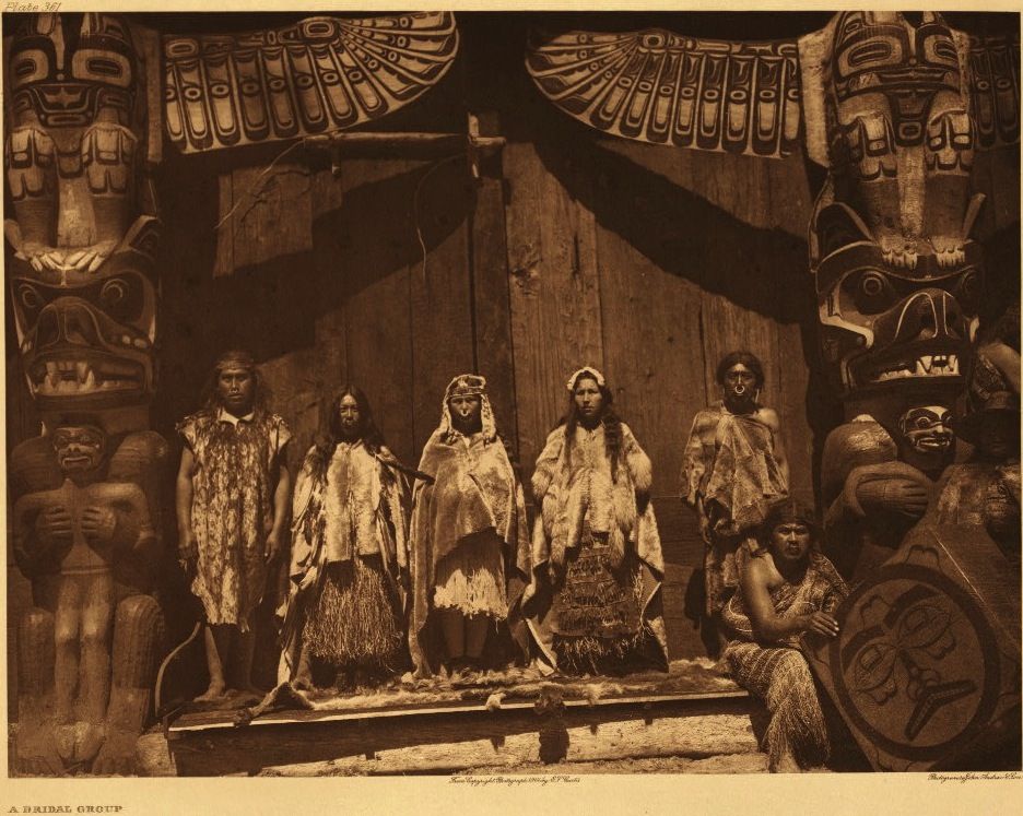 Edward Curtis photo of a Kwakwaka'wakw potlatch with dancers and singers. Kwakwaka'wakw people in a wedding ceremony, bride in centre. Photo