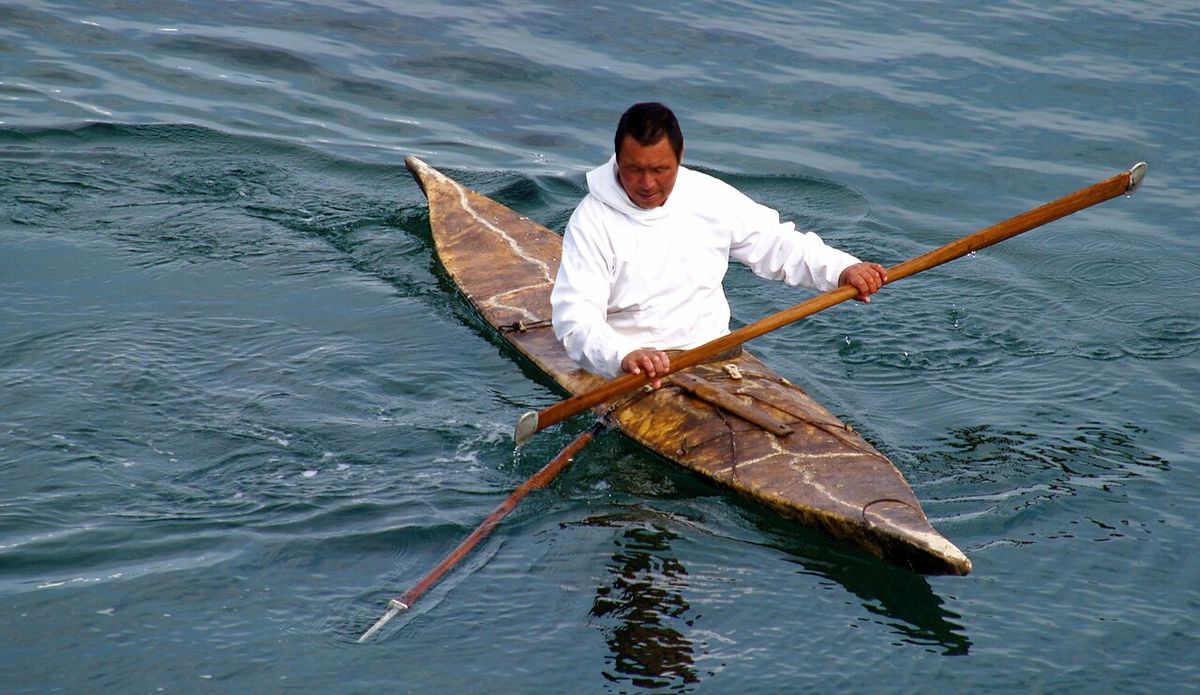 Inuit seal hunter in a kayak armed with a harpoon. Kulusuk, Greenland.