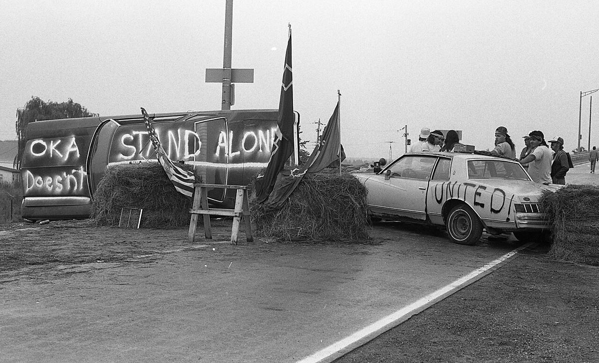 Men and women from the Tyendinaga Mohawk Territory blockading the Skyway Bridge over the Bay of Quinte. A sign spray-painted on an overturne