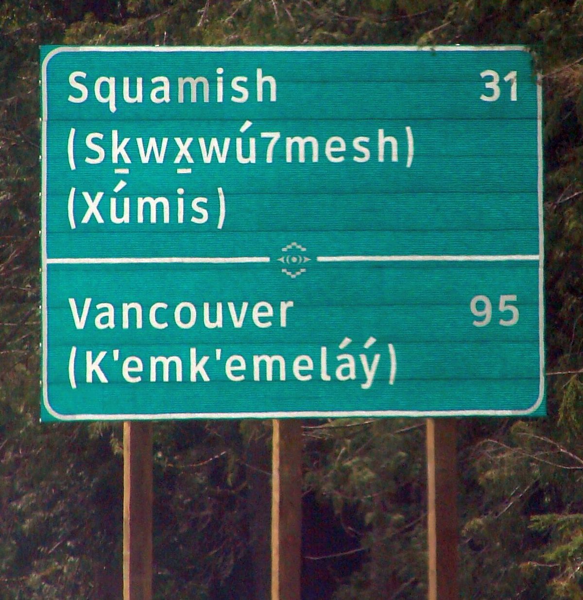 Photo of bilingual road sign in English and in Squamish, taken in British Columbia, Canada, showing the digit 7 as replacement for the simil