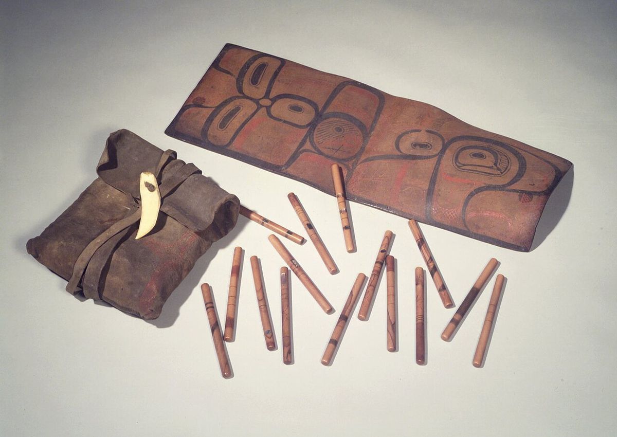 Tsimshian (Native American). Bag with 65 Inlaid Gambling Sticks (QsEn), 19th century. Maple wood, abalone, pigment, hide, tooth, bag: 6 1/4