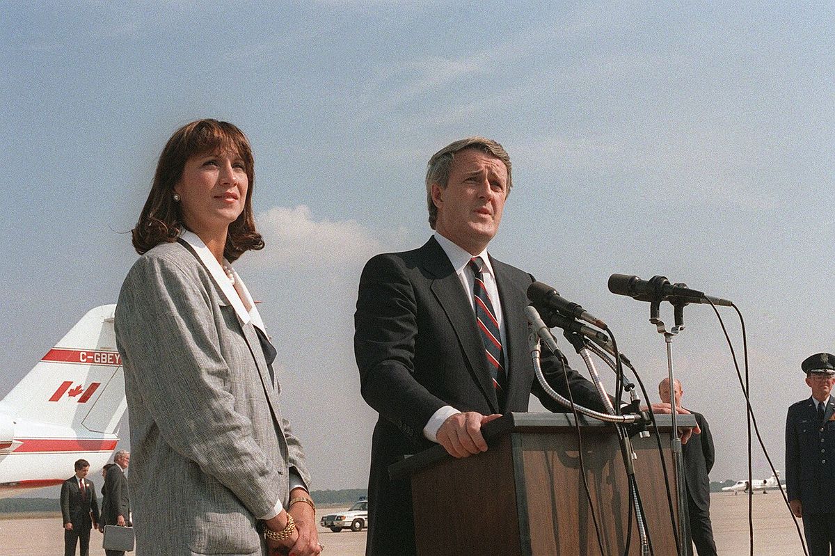 Canadian Prime Minister Brian Mulroney bids farewell to dignitaries after a state visit. Mulroney is accompanied by his wife, Mila. Location